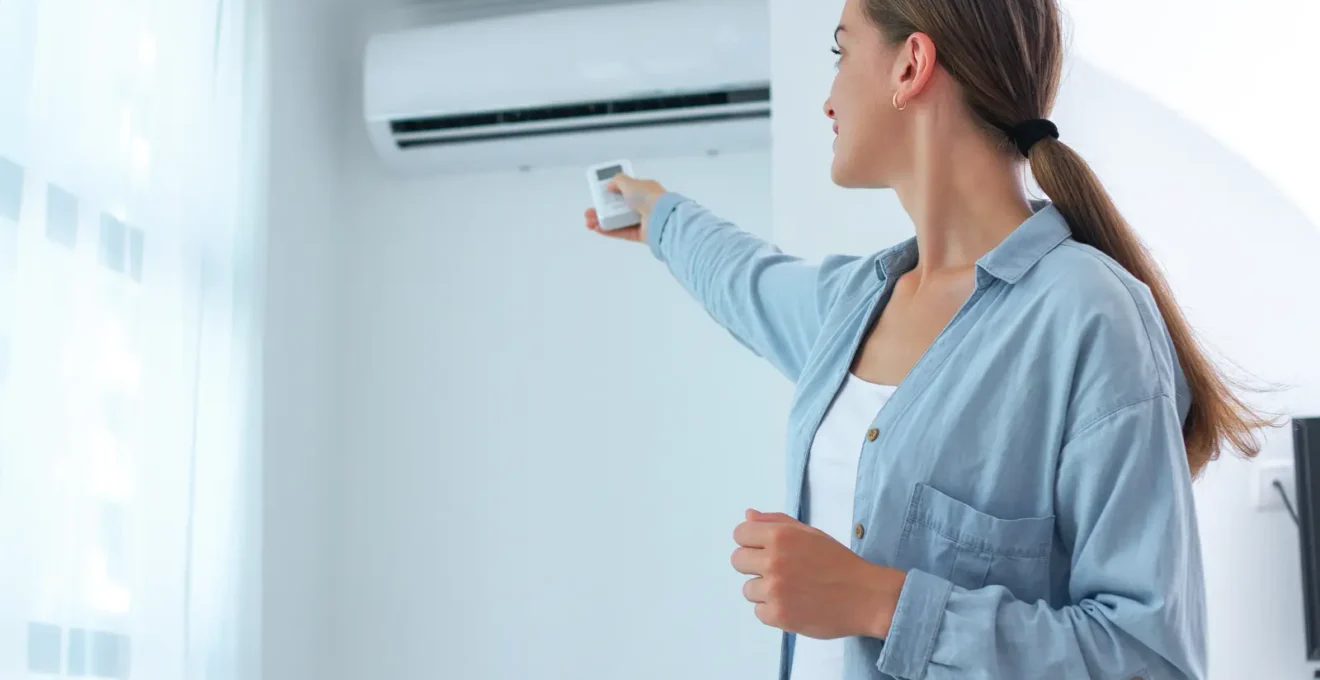 Une personne ajuste un émetteur mural intérieur dans un salon ensoleillé.